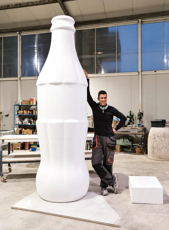 Bouteille géante blanche à l'atelier, à côté d'un artisan