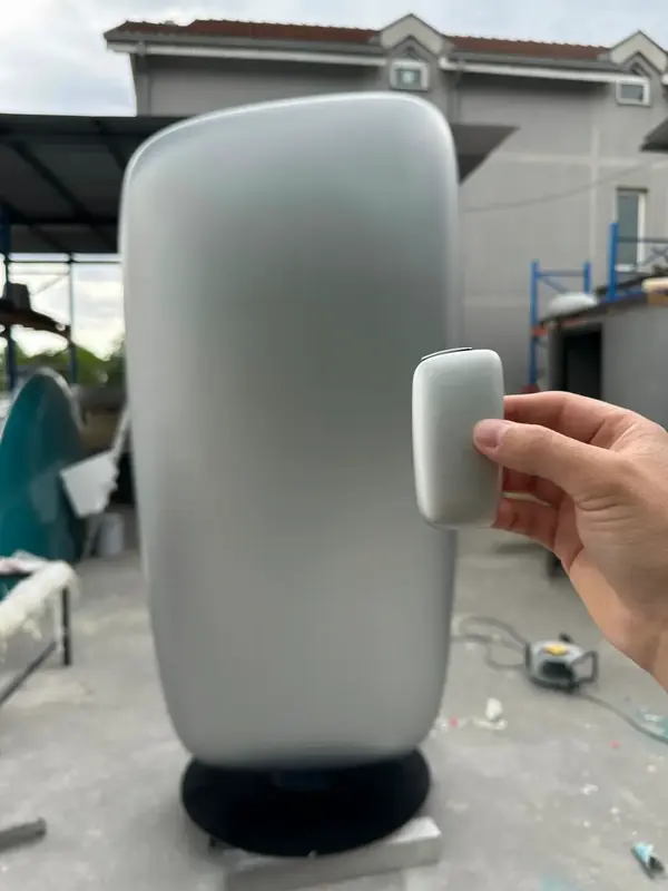 Une main tient un petit appareil devant sa réplique géante
