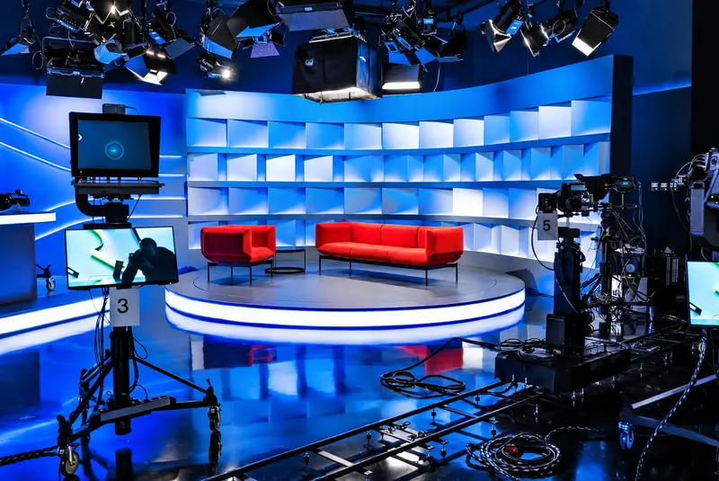 Plateau TV circulaire, canapés rouges et lumière bleue